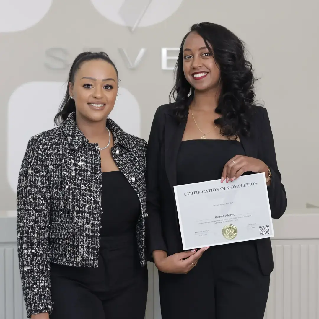 Permanent Makeup Certification at Seven Aesthetics: Teacher Betlehem Bereket with student Raniel Alemu holding her certificate of completion after completing the course.