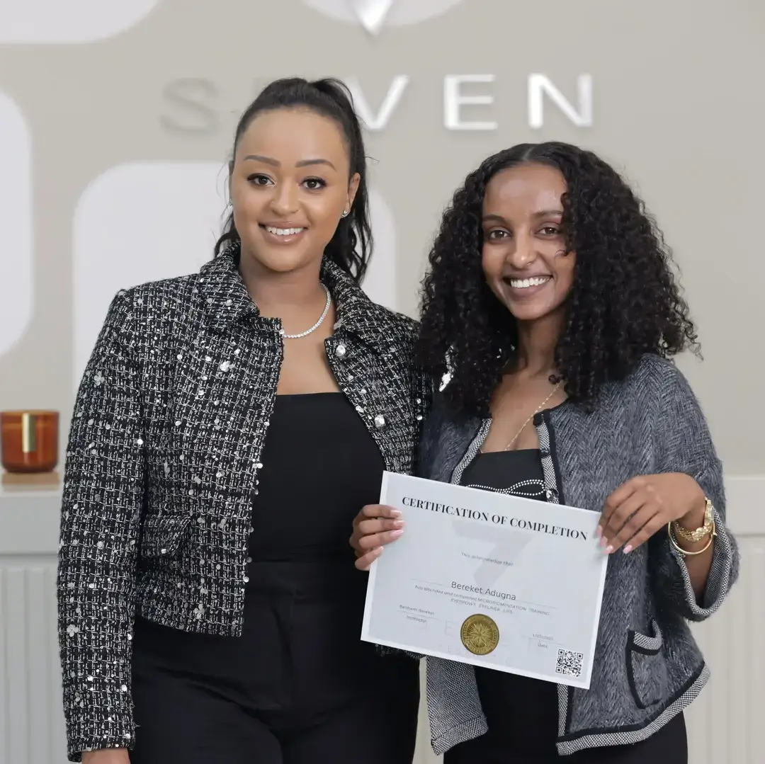 Permanent Makeup Certification at Seven Aesthetics: Teacher Betlehem Bereket with student Birkelesh Adugna holding her certificate of completion after completing the course.